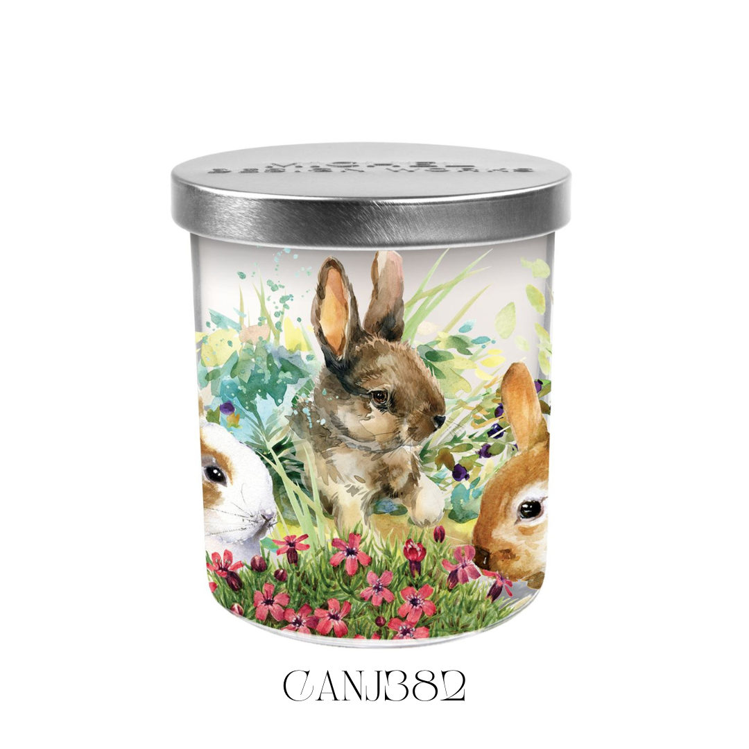 Bunny Meadow Candle Jar with Lid, featuring a beautifully detailed artwork of charming bunnies on the glass jar. The soy blend candle offers a gentle scent of blooming flowers with a hint of cucumber, with a burn time of approximately 38 hours