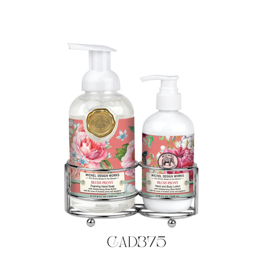 Hand Care Caddy Blush Peony featuring a foaming hand soap and a rich hand and body lotion, both with an elegant fragrance of aromatic peony, hints of mandarin, gardenia, cedar, and sandalwood. Set in a stylish silver-toned caddy, perfect for adding a touch of elegance and romance to kitchen counters or guest bathrooms