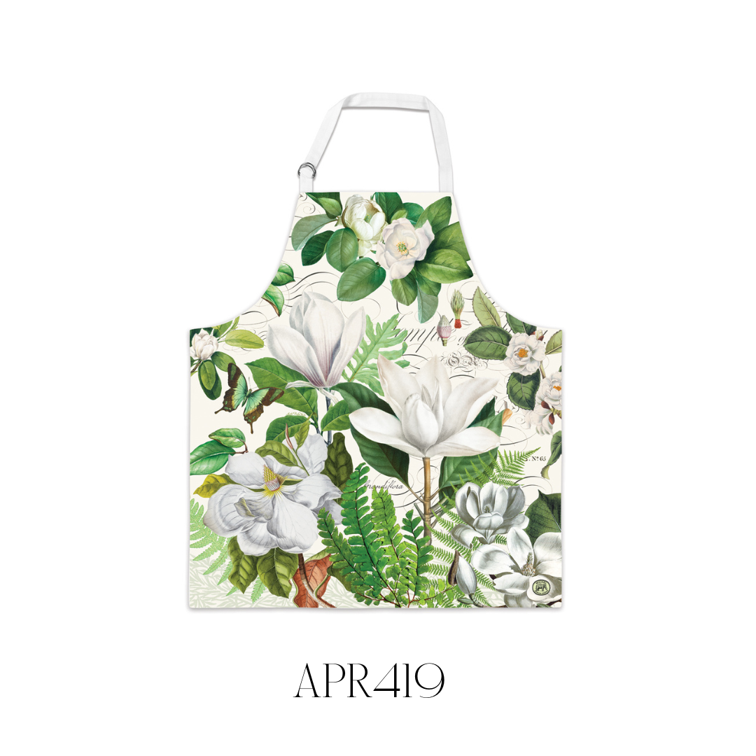 Magnolia Petals Chef’s Apron laid flat, made of 100% cotton with a beautiful floral design that coordinates with matching kitchen towels. The apron features adjustable metal D-rings at the neck for a comfortable fit and measures 69.8 x 80 cm, making it a stylish and practical kitchen accessory