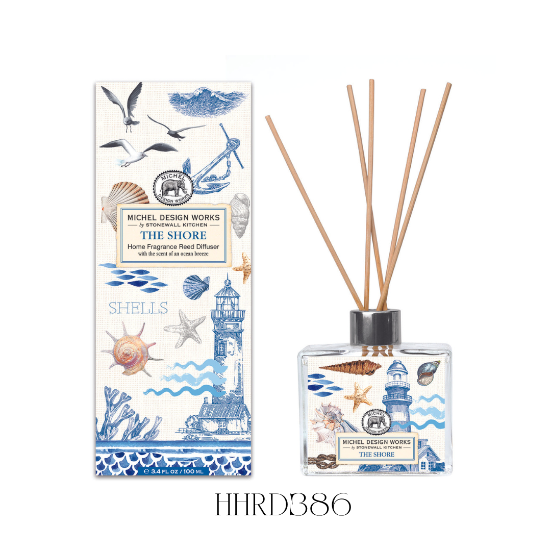 The Shore Reed Diffuser displayed on a bathroom shelf, showcasing the elegant glass decanter with detailed coastal artwork and eight reeds. The diffuser releases a fresh blend of ocean water, floral notes, and mandarin, ideal for creating a calming beach-inspired atmosphere in any room.