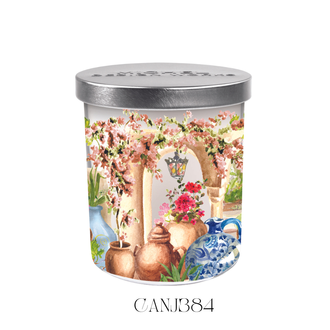 Lit Tuscan Terrace Candle Jar with its lid beside it, showcasing the vibrant artwork on the glass and the warm glow of the soy blend wax. The candle emits a rich, floral scent of hyacinth, mums, lilac, with subtle notes of fig and musk, perfect for creating a relaxing ambiance